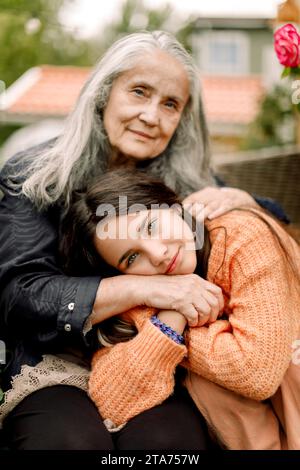 Ritratto di una nipote sorridente che tiene per mano e abbraccia la nonna Foto Stock