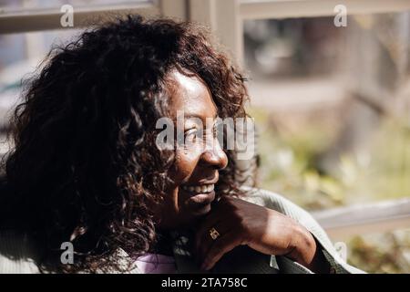 Donna matura felice con i capelli neri che guarda lontano da casa Foto Stock