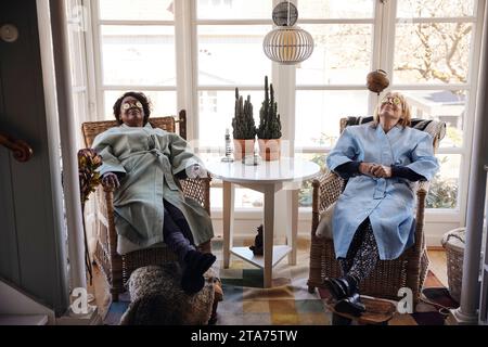 Amici femminili multirazziali con fette di cetriolo sugli occhi che si rilassano insieme a casa Foto Stock