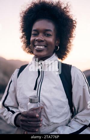 Ritratto di una giovane donna sorridente che tiene in mano una bottiglia d'acqua Foto Stock