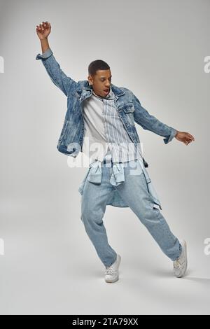 affascinante uomo afro-americano con elegante outfit in denim che mostra un vivace concetto di moda Foto Stock