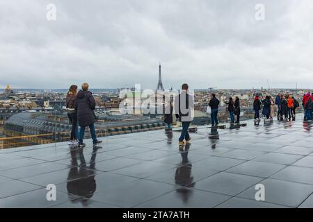 Parigi, Francia, 2023. I visitatori si godono la vista dal tetto delle Galeries Lafayette in una giornata di pioggia, con la Torre Eiffel sullo sfondo Foto Stock