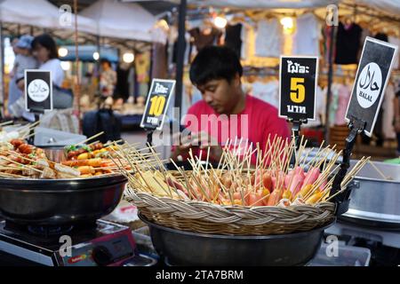 Tailandese che vende spuntini di carne al mercato notturno per i turisti Foto Stock