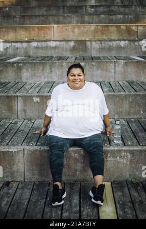 Ritratto di una donna sorridente che si rilassa sui gradini Foto Stock