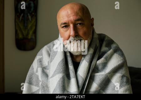 Ritratto di un uomo serio maturo avvolto in una coperta a casa Foto Stock