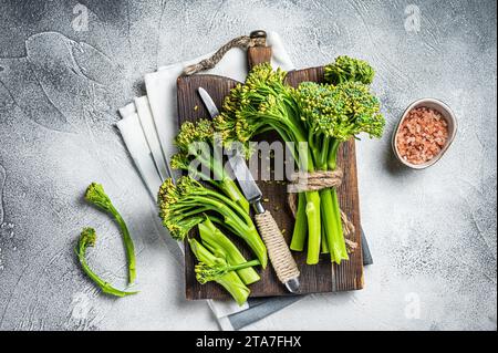 Mazzo fresco di broccolini su tagliere pronto per la cottura. Sfondo bianco. Vista dall'alto. Foto Stock