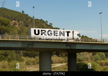 Un veicolo sta attraversando il ponte, con l'iscrizione sul rimorchio - urgente. Concetto di logistica. Foto Stock