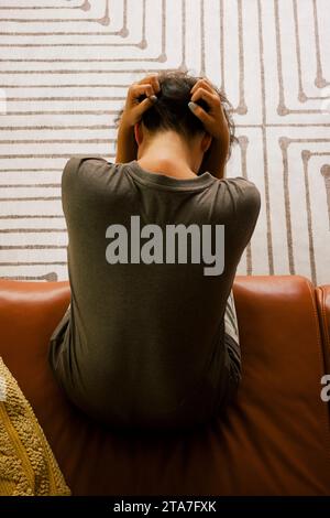 Direttamente sopra la vista di una donna solitaria seduta sul divano a casa Foto Stock