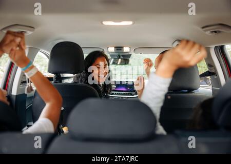 I genitori felici si divertono con le figlie in macchina durante il viaggio in auto Foto Stock