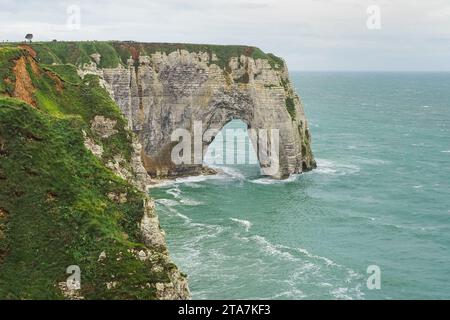 Vista panoramica sulla bianca roccia di Étretat la Manneporte. Ripida scogliera di gesso verticale con arco naturale e spiaggia sottostante, bagnata dalla tempesta dell'Oceano Atlantico Foto Stock