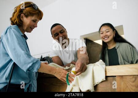 Abito di misurazione personalizzato sorridente del cliente utilizzando il metro a nastro in negozio Foto Stock
