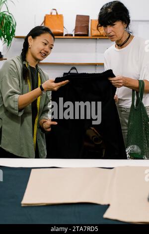Personale di vendita donna che mostra pantaloni a donna mentre fa acquisti in negozio Foto Stock