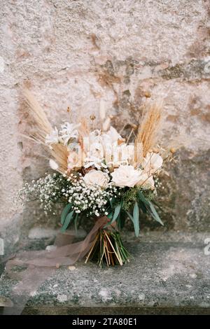 Il bouquet sposa si trova vicino alle mura di un antico edificio in pietra Foto Stock