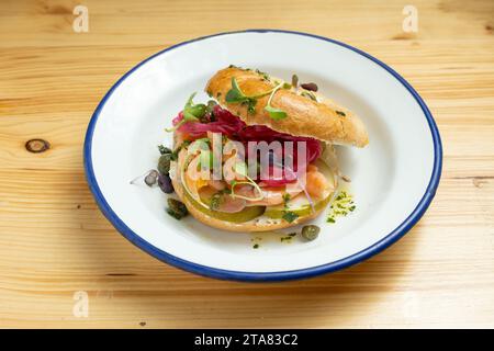 Primo piano del panino con bagel al salmone affumicato su una tavola di legno Foto Stock