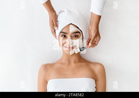 Una bella donna orientale gode di un trattamento facciale ringiovanente Foto Stock