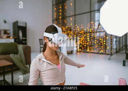 Durante le festività natalizie, un personal trainer conduce sessioni di fitness virtuale a casa tramite un visore per la realtà virtuale. Foto Stock