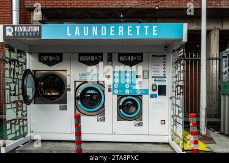 Lavanderia automatica self-service con lavatrici e asciugatrici industriali in ambiente urbano. Foto Stock