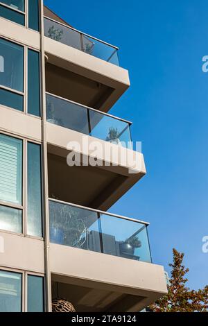 Moderni edifici di appartamenti in una giornata di sole con un cielo blu. Facciata di un moderno edificio di appartamenti con balconi in vetro. Nuovo ed elegante design multilivello Foto Stock