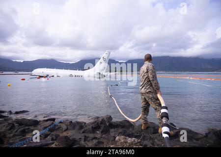 Kaneohe Bay, Stati Uniti. 26 novembre 2023. Un Marine degli Stati Uniti tiene una manichetta di carburante fissata durante le operazioni di srifornimento su un aereo P-8A Poseidon della Marina degli Stati Uniti abbattuto che ha sorpassato la pista in acqua presso la base aerea del corpo dei Marines di Kaneohe Bay, il 26 novembre 2023 a Kaneohe Bay, Hawaii. Credito: Sgt. Brandon Aultman/U.S. Marine Corps/Alamy Live News Foto Stock