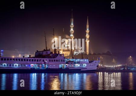 Traghetti per Istanbul. Traghetto e Eminonu Yeni Cami o la nuova moschea nella notte nebbiosa dal ponte Galata. Istanbul, Turkiye Foto Stock