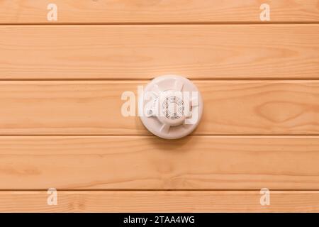 Allarme antincendio sul soffitto in legno per la sicurezza del rilevatore di fumo e la protezione domestica da pericoli con incendio, primo piano. Foto Stock