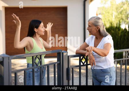 Vicini emotivi che discutono vicino alla recinzione all'aperto Foto Stock