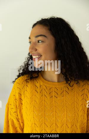 Profilo di felice donna birazziale in maglione giallo a casa Foto Stock