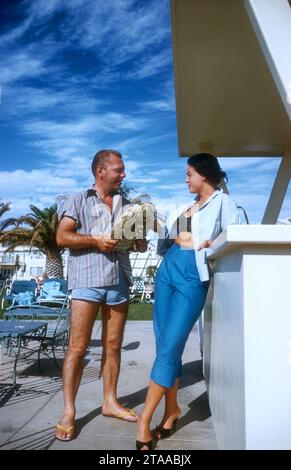 LAS VEGAS, NV - 1958: L'attrice e modella Kitty Dolan parla con la sua amica a bordo piscina intorno al 1958 a Las Vegas, Nevada. (Foto di Hy Peskin) *** didascalia locale *** Kitty Dolan Foto Stock