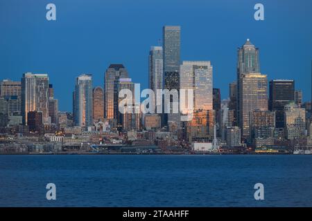 Seattle - 20 novembre 2023; il panorama urbano del centro di Seattle dello skyline del quartiere degli affari al tramonto con riflessi del sole arancione Foto Stock