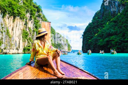 Donne asiatiche di fronte a una barca a coda lunga a Kho Phi Phi Thailandia, donne di fronte a una barca alla laguna di Pileh con oceano colorato di turchouse durante una gita in barca alla Baia Maya Koh Phi Phi Foto Stock