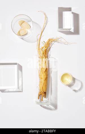 Scena minima per pubblicità e branding di prodotti con ingredienti vegetali coreani. Un fresco ginseng su vaso di vetro decorato con alcuni podi di vetro Foto Stock