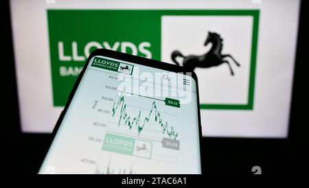 Telefono cellulare con sito Web della società finanziaria britannica Lloyds Banking Group plc davanti al logo aziendale. Mettere a fuoco in alto a sinistra sul display del telefono. Foto Stock