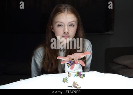 La ragazza adolescente lascia cadere dalla sua mano pezzi di un puzzle e si disperdono Foto Stock