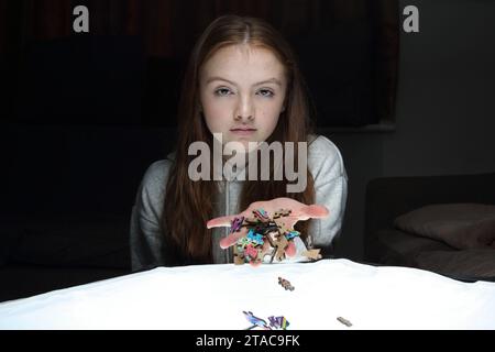 La ragazza adolescente lascia cadere dalla sua mano pezzi di un puzzle e si disperdono Foto Stock