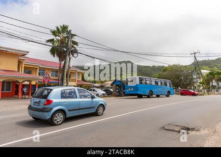 Anse Royale, Seychelles - 18 agosto 2023: Vista sulla strada con auto e autobus, gente del posto che cammina per la strada Foto Stock