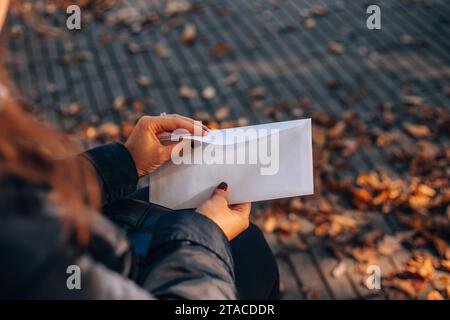 La ragazza apre una busta bianca con un assegno. Assegno retributivo. Tenendo in mano un assegno di stipendio. Donna con stipendio. Foto Stock