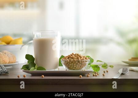 Colazione salutare con bevanda di soia vegetale in un bicchiere e semi su una panca da cucina in legno. Vista frontale. Foto Stock