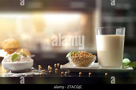 Colazione con un bicchiere completo di latte di soia, semi, farina e pane di soia su panca nera da cucina. Vista frontale. Foto Stock