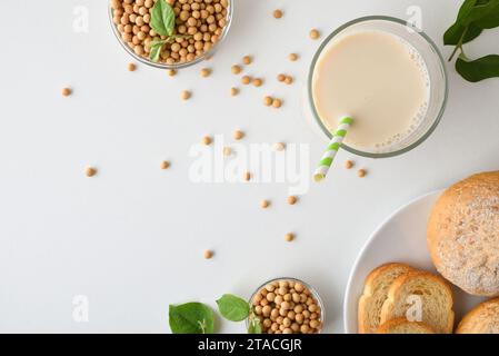 Colazione con latte e pane di soia su un tavolo bianco con ciotole piene di cereali e foglie vista dall'alto. Vista dall'alto. Foto Stock