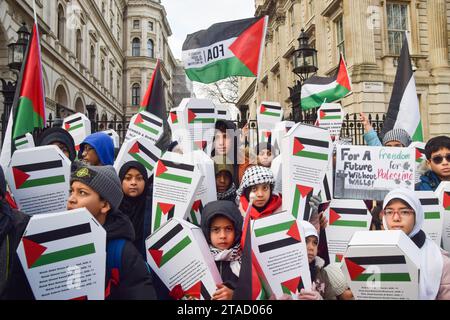 Londra, Inghilterra, Regno Unito. 30 novembre 2023. I bambini tengono in mano "bara dei bambini" di cartone fuori Downing Street, che rappresenta oltre 6000 bambini palestinesi uccisi dalle forze israeliane, chiedendo un cessate il fuoco permanente mentre Israele interrompe i combattimenti con Hamas. (Immagine di credito: © Vuk Valcic/ZUMA Press Wire) SOLO USO EDITORIALE! Non per USO commerciale! Foto Stock