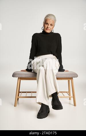ritratto di lavoro, felice donna d'affari di mezza età in un elegante abbigliamento informale seduta su una panca interna Foto Stock