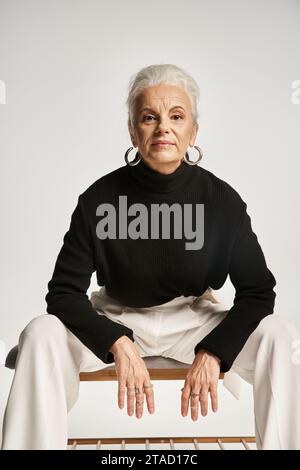 ritratto di lavoro, felice donna d'affari di mezza età in un elegante abbigliamento informale seduta su una panca interna Foto Stock