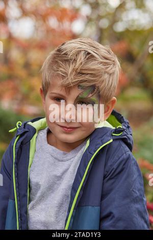 Capodanno 2024 in maschera - ragazzo con pittura drago sul volto. Simbolo del calendario cinese tradizionale. Foto Stock