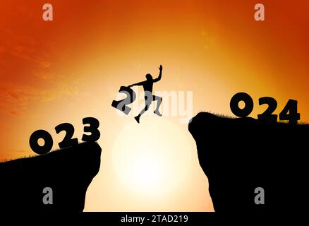 Silhouette Man salta per rendere felice il nuovo anno 2024 con l'alba. Il nuovo anno 2024 sta arrivando. Foto Stock