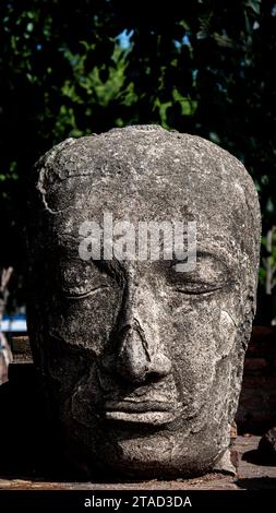 Una scultura di una figura maschile si trova sullo sfondo di una strada rocciosa Foto Stock