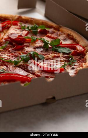 Pizza grande con peperoni e peperoni in una scatola di cartone aperta, vista ravvicinata Foto Stock
