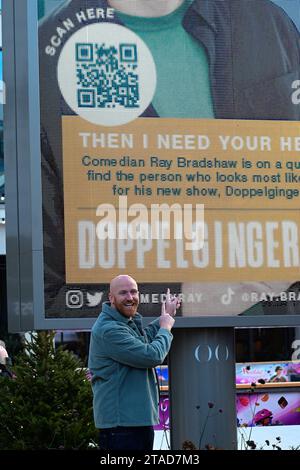 Westfield White City, Londra, Regno Unito. 30 novembre 2023. Il comico Ray Bradshaw lancia la sua ricerca mondiale per il suo alter ego. Nella foto, Ray Bradshaw ha rilevato un cartellone al Westfield White City oggi dando il via alla sua ricerca e al suo tour nel Regno Unito dal titolo "Doppelginger". Maggiori informazioni e biglietti su raybradshaw.com. Credito: Vedere li/Picture Capital/Alamy Live News Foto Stock