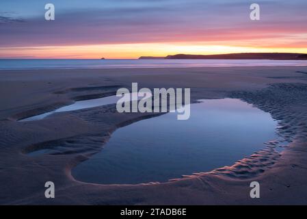 Alba colorata sulle piscine di marea su una deserta Harlyn Beach, Cornovaglia, Inghilterra. Primavera (aprile) 2022. Foto Stock