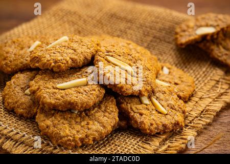 Vista ad alto angolo, pila di croccanti biscotti al cocco fatti in casa su un panno di legno. Foto Stock