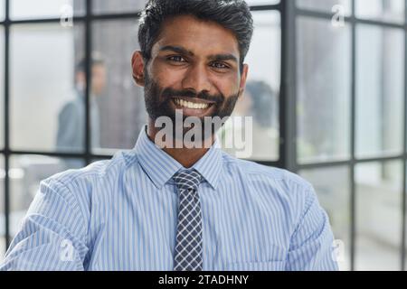 la barba di un investitore maschile che guarda la fotocamera e sorride in un ufficio moderno Foto Stock